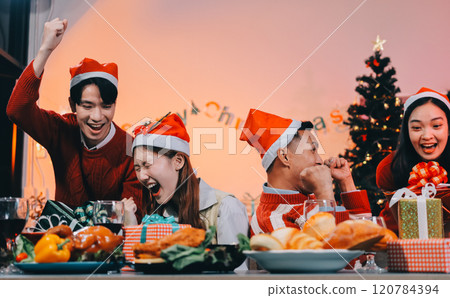 Group of happy Asian friends celebrating Christmas and decorate the Christmas tree indoors. Beauty woman with Christmas Gifts. New Year party. Woman hands decorate Christmas tree red ball, bauble. 120784394