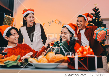 Group of young Asian man and women as friends having fun at a New Year's celebration, holding gift boxes standing by Christmas tree decoration, midnight countdown Party at home with holiday season. Group of young Asian man and women as friends having fun at a New Year's celebration, holding gift boxes standing by Christmas tree decoration, midnight countdown Party at home with holiday season. 120784399