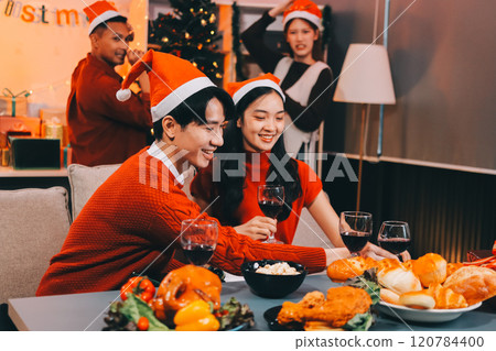 Group of young Asian man and women as friends having fun at a New Year's celebration, holding gift boxes standing by Christmas tree decoration, midnight countdown Party at home with holiday season. Group of young Asian man and women as friends having fun at a New Year's celebration, holding gift boxes standing by Christmas tree decoration, midnight countdown Party at home with holiday season. 120784400