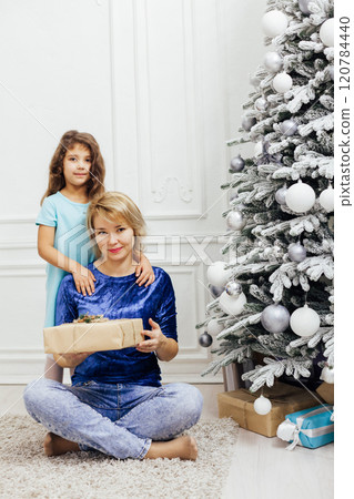 Mother with daughter at Christmas tree with gifts garlands decorated for the new year 120784440