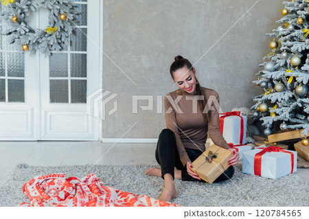 Woman at home at Christmas tree with gifts toys decorated 120784565