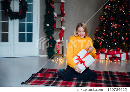 Beautiful woman smiling at christmas tree with gifts toys garlands for new year Beautiful woman smiling at christmas tree with gifts toys garlands for new year 120784615