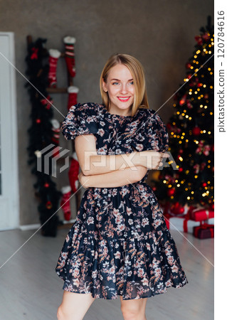 Beautiful woman smiling at christmas tree with gifts toys garlands for new year Beautiful woman smiling at christmas tree with gifts toys garlands for new year 120784616