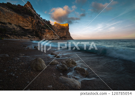 The rock rises above the blue sea at sunset or sunrise The rock rises above the blue sea at sunset or sunrise 120785054