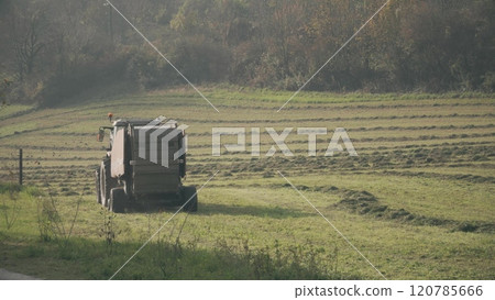 A tractor with hay baler or hay maker trailer in the field A tractor with hay baler or hay maker trailer in the field 120785666