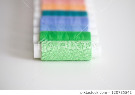 Many colorful sewing threads on light background. Many colorful sewing threads on light background. 120785841