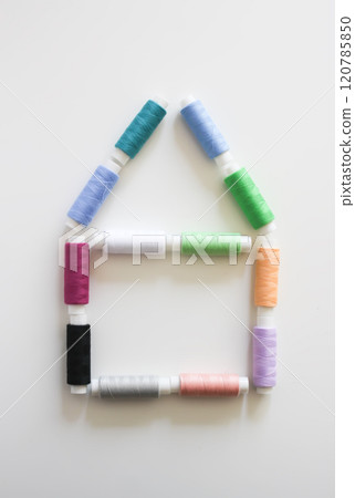 Many colorful house-shaped sewing threads on light background. 120785850