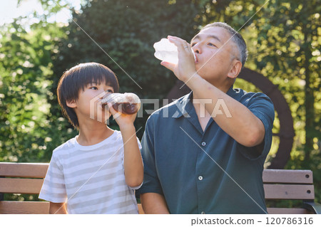 Grandson and grandfather enjoying a drink together 120786316