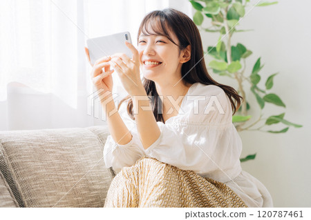 Woman sitting on a sofa and looking at a smartphone 120787461