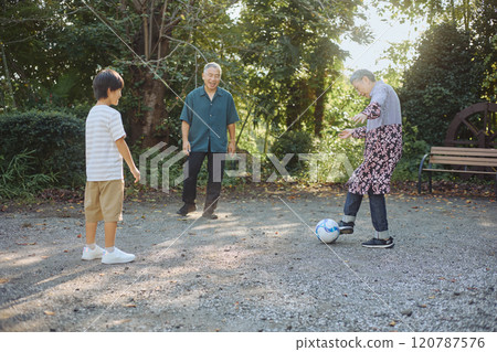 Senior couple and grandchild playing soccer 120787576
