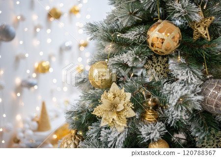 Christmas tree with gold toys. Festively decorated Christmas tree with garlands. Symbol of the new year in trend colors 120788367