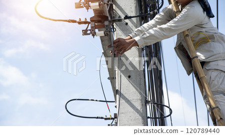 The technician is repairing the cables on the electric pole. 120789440