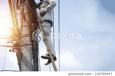The technician is repairing the cables on the electric pole. 120789441