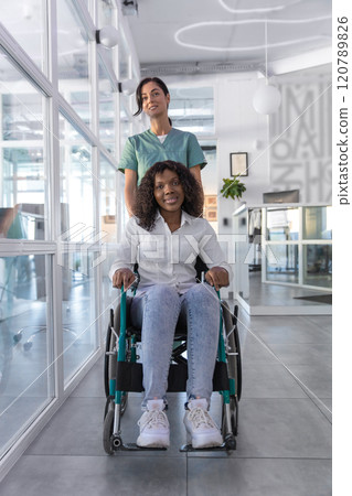 Female nurse carrying a wheelchair with an african american woman 120789826