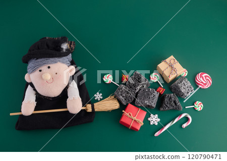 The Befana with sweet coal and candy on green background. Italian Epiphany day tradition 120790471