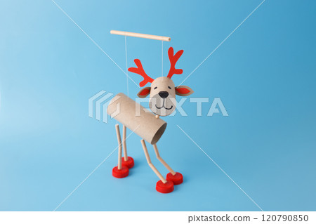 DIY reindeer puppet made from cardboard tubes, red bottle caps, paper details. on a blue background. Christmas craft and holiday decoration concept. toilet paper roll craft for kid and kindergarten, 120790850