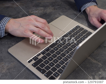 Businessman working on a gold laptop in a modern office, browsing online with focus and efficiency. Businessman working on a gold laptop in a modern office, browsing online with focus and efficiency. 120791087