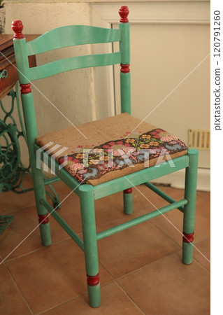 Retro chair makeover into boho style with folk motif embroidered burlap reupholstery of seat. Green painted chair with ethnic upholstery. Renovated furniture with embroidery on seat. Boho interior 120791260
