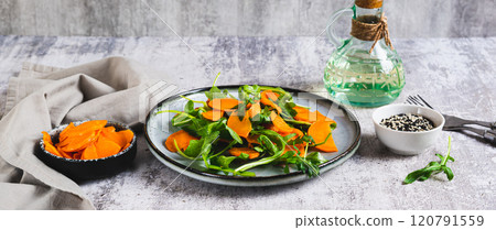 Roasted sweet potato and fresh arugula salad on a plate on the table web banner Roasted sweet potato and fresh arugula salad on a plate on the table web banner 120791559