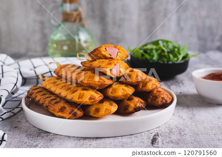 Stack of homemade corn dogs with sausage on a plate on a table Stack of homemade corn dogs with sausage on a plate on a table 120791560