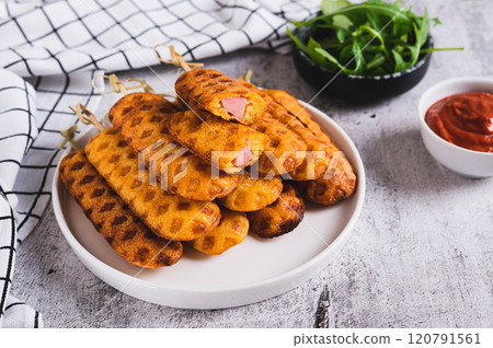 Grilled corn dogs with sausage on a plate and ketchup on the table Grilled corn dogs with sausage on a plate and ketchup on the table 120791561