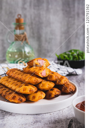 Stack of homemade corn dogs with sausage on a plate on a table vertical view Stack of homemade corn dogs with sausage on a plate on a table vertical view 120791562