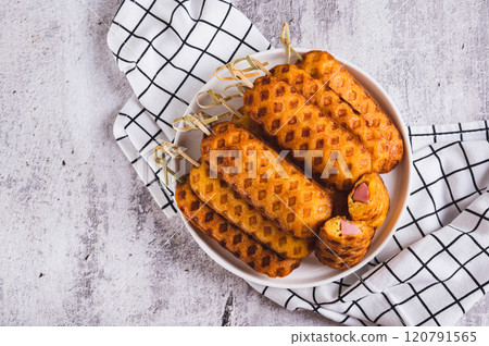 Close up of stack of homemade corn dogs with sausage on a plate on a table top view Close up of stack of homemade corn dogs with sausage on a plate on a table top view 120791565