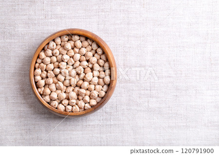 Dried chickpeas in a wooden bowl, on linen fabric, with empty space for text. Whole and light tanned chick peas, a high in protein legume and fruit of Cicer arietinum, and a key ingredient in hummus. Dried chickpeas in a wooden bowl, on linen fabric, with empty space for text. Whole and light tanned chick peas, a high in protein legume and fruit of Cicer arietinum, and a key ingredient in hummus. 120791900