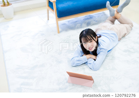 年輕女性躺著，在平板電腦上觀看 YouTube 視頻，在假期放鬆，觀看視頻 120792276