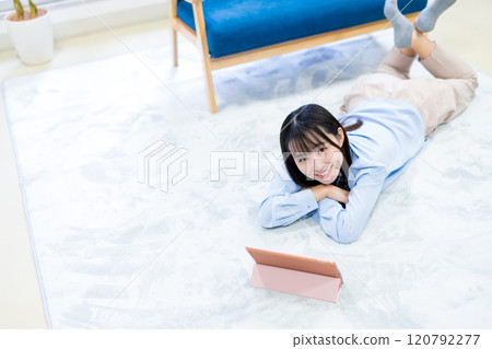 年輕女性躺著，在平板電腦上觀看 YouTube 視頻，在假期放鬆，觀看視頻 120792277