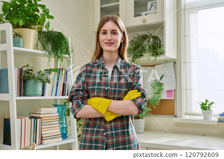 Portrait of young woman wearing gloves for cleaning, with arms crossed, in home 120792609