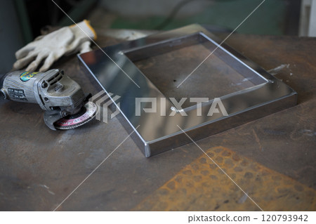 Finishing work on the welded part with a grinder 120793942