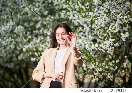 Woman allergic suffering from seasonal allergy at spring. Young happy woman showing pill, posing in blossoming garden at springtime. Antihistamine medication concept 120793981
