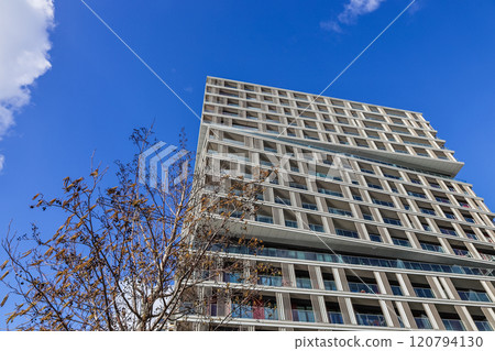 Modern High-Rise Residential Building with Glass Balconies and a Clear Blue Sky 120794130