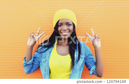 Pretty smiling young african woman having fun over orange background Pretty smiling young african woman having fun over orange background 120794189