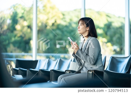 Office lady looking at smartphone, woman waiting for someone in airport lobby, office lady, working 120794513