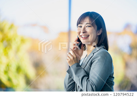 A female office worker talking on a smartphone, a woman waiting for someone in an airport lobby, an office lady working 120794522