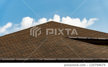 Bitumen tile roof. Newly built house roof top is covered with asphalt shingles. Building 120794674