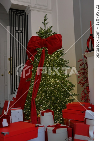 large Christmas tree with red bow and toys. New Year's decor, gift box on Christmas Eve. large Christmas tree with red bow and toys. New Year's decor, gift box on Christmas Eve. 120795322