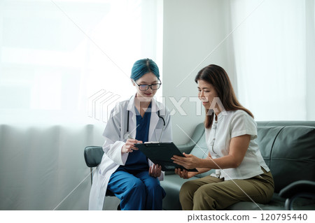 A woman and a doctor are sitting on a couch, looking at a clipboard 120795440