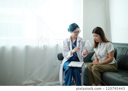 A woman is sitting on a couch while a doctor shows her a toothbrush A woman is sitting on a couch while a doctor shows her a toothbrush 120795443