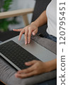 A woman is sitting on a couch with a laptop on her lap 120795451
