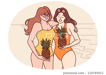 Women in swimsuits stand on beach with pineapples in hands and smile inviting visit tropical island 120795651