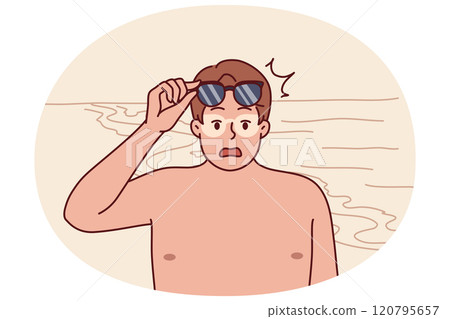Tanned man takes off sunglasses and screams after getting sunburn relaxing on beach 120795657