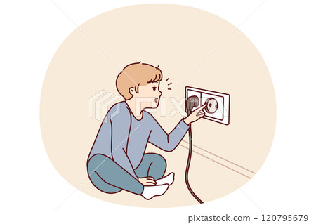 Small boy sticks fingers into socket, playing with electrical equipment and risking electric shock 120795679