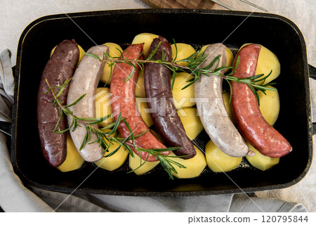Close-up of bowl with raw homemade blood sausage, pork sausage and chorizo in oven with potatoes. homemade traditional food Close-up of bowl with raw homemade blood sausage, pork sausage and chorizo in oven with potatoes. homemade traditional food 120795844