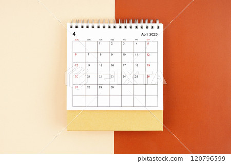 Directly above view of April 2025 desk calendar on orange background. 120796599