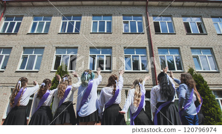Graduating students waving goodbye to their school as they celebrate the end of an era and the beginning of a new chapter 120796974