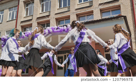 High school seniors celebrate their last day by dancing in a circle wearing purple ribbons 120796978