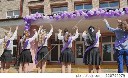 Graduates saying farewell to their school on their final day, adorned with purple ribbons and rejoicing with balloons Graduates saying farewell to their school on their final day, adorned with purple ribbons and rejoicing with balloons 120796979
